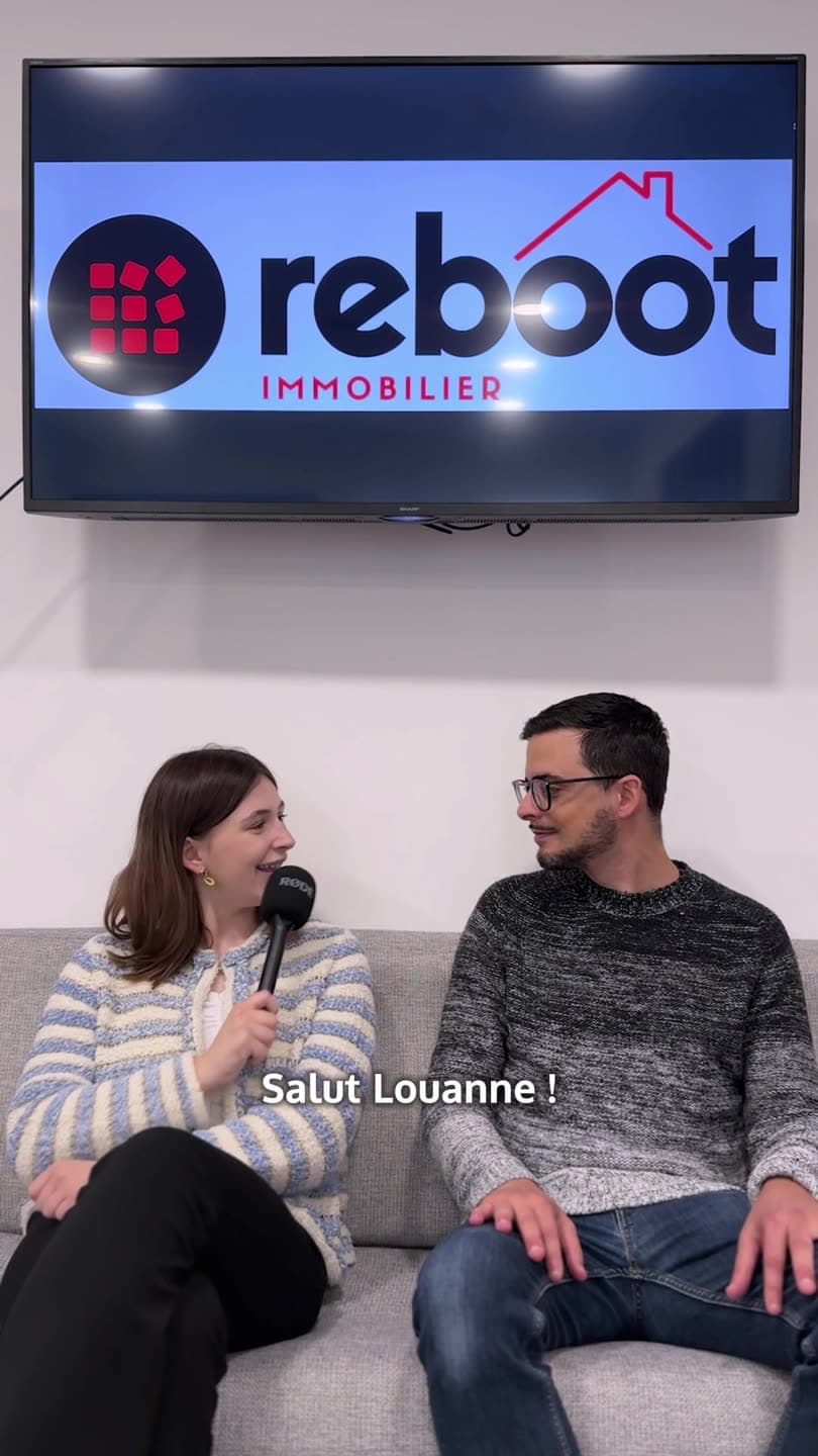 Dan Medina et Louane assis sur un canapé, sous l'écran à l'enseigne Reboot Immobilier